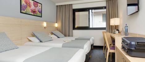 Quarto de hotel com duas camas, uma escrivaninha, uma cadeira, uma televisão e uma janela com cortinas.