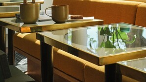 A modern interior with a sofa, a glass table, and a potted plant. - Hôtel Orphée - Orso hotel (Paris)