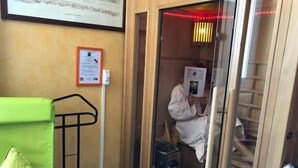 A sauna room with a wooden door, a towel rack, and a framed certificate on the wall. - La Croix Blanche (Tarbes)