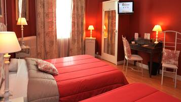 Camera d'albergo con due letti, una scrivania, una sedia, un televisore e un termosifone.