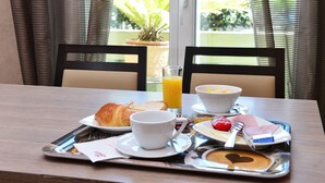 A breakfast tray with croissants, orange juice, a bowl of cereal, a plate with ham and eggs, and a heart-shaped pancake on a tray. - La Croix Blanche (Tarbes)