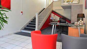 A modern office space with a staircase, a desk with a computer, and a red chair.