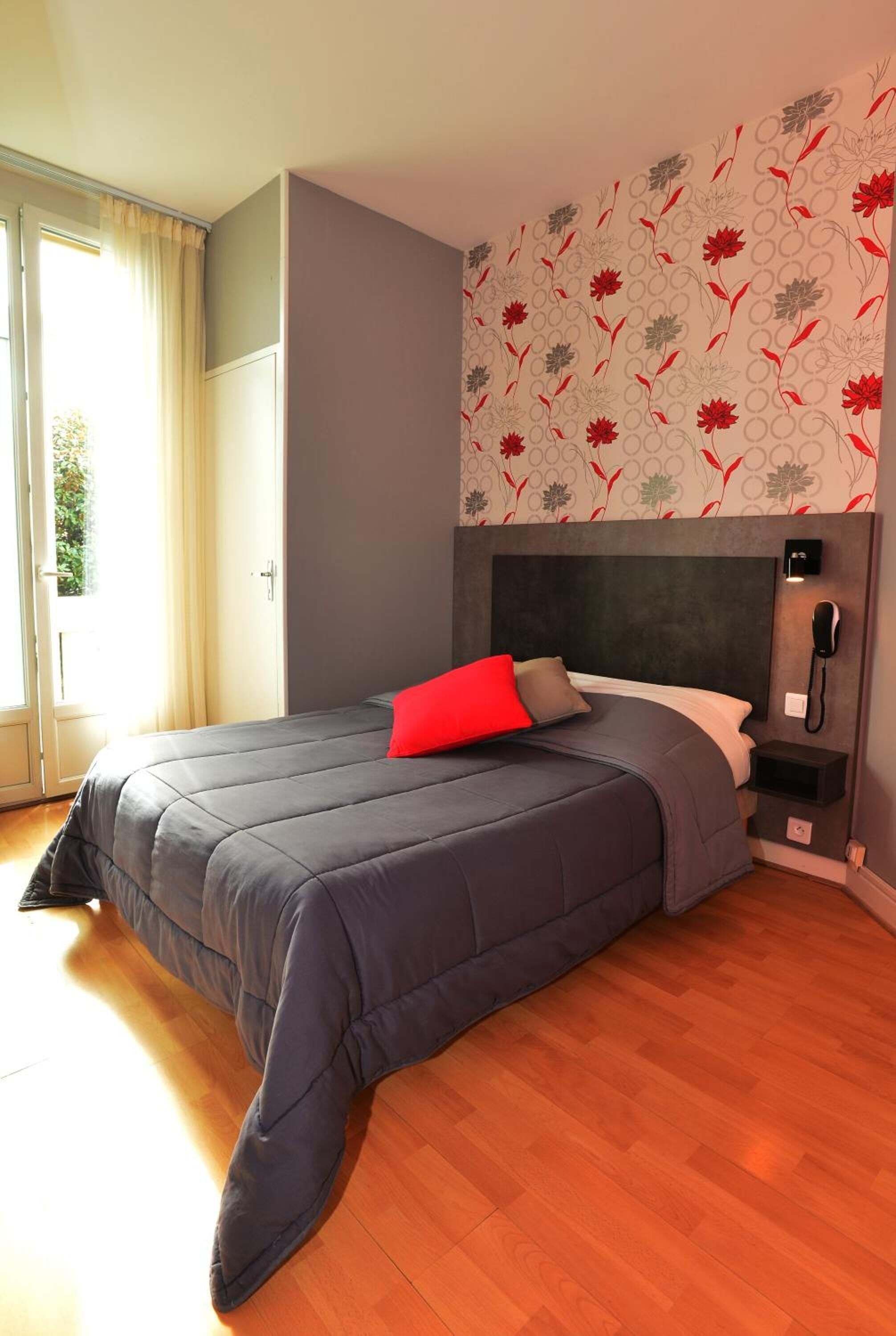 Un dormitorio con una cama grande, un teléfono en la mesita de noche y una ventana con cortinas.