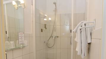 A modern bathroom with a glass-enclosed shower, a white sink, and a mirror with lights.
