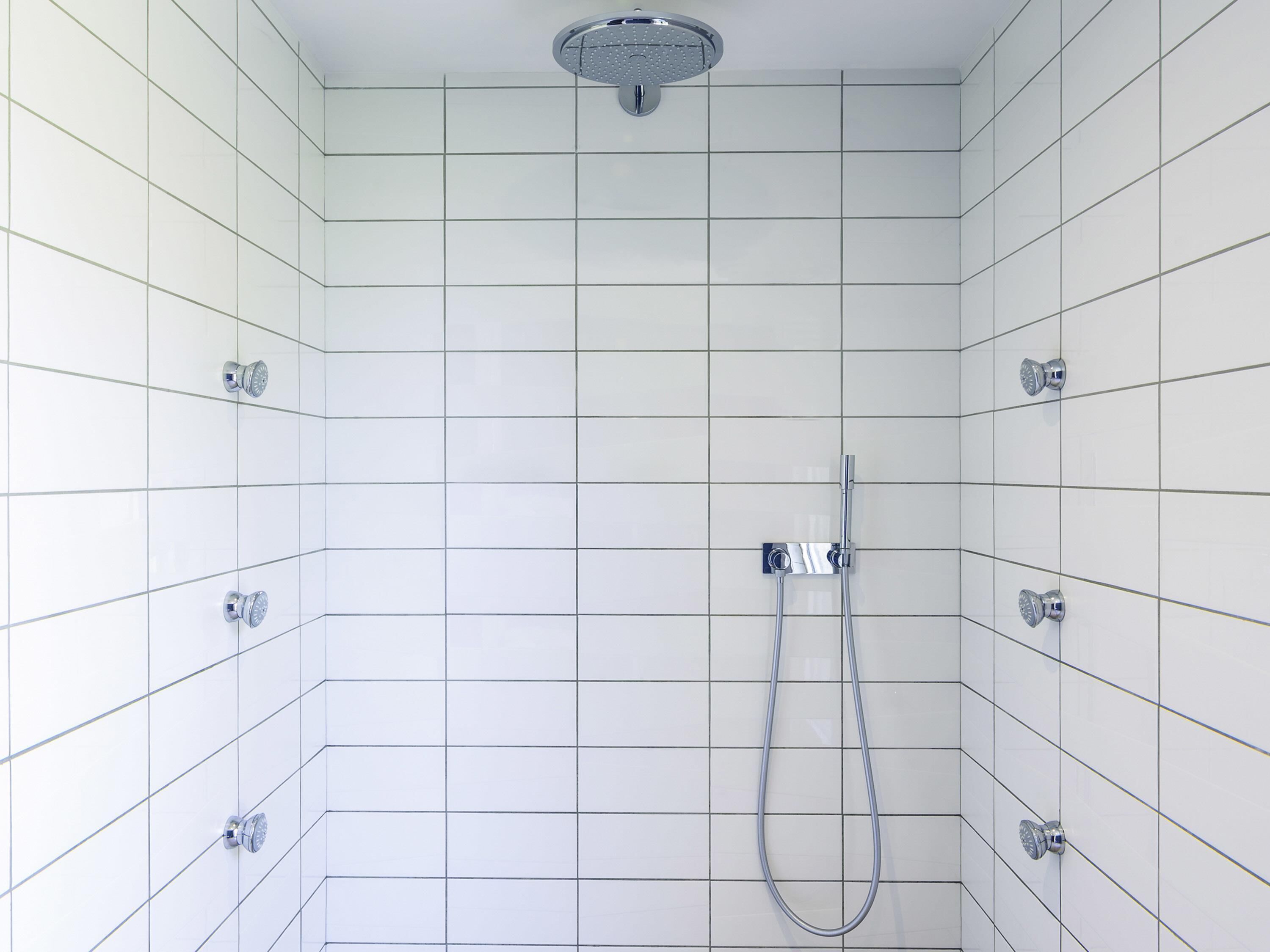 A shower with a handheld showerhead and a wall-mounted faucet.