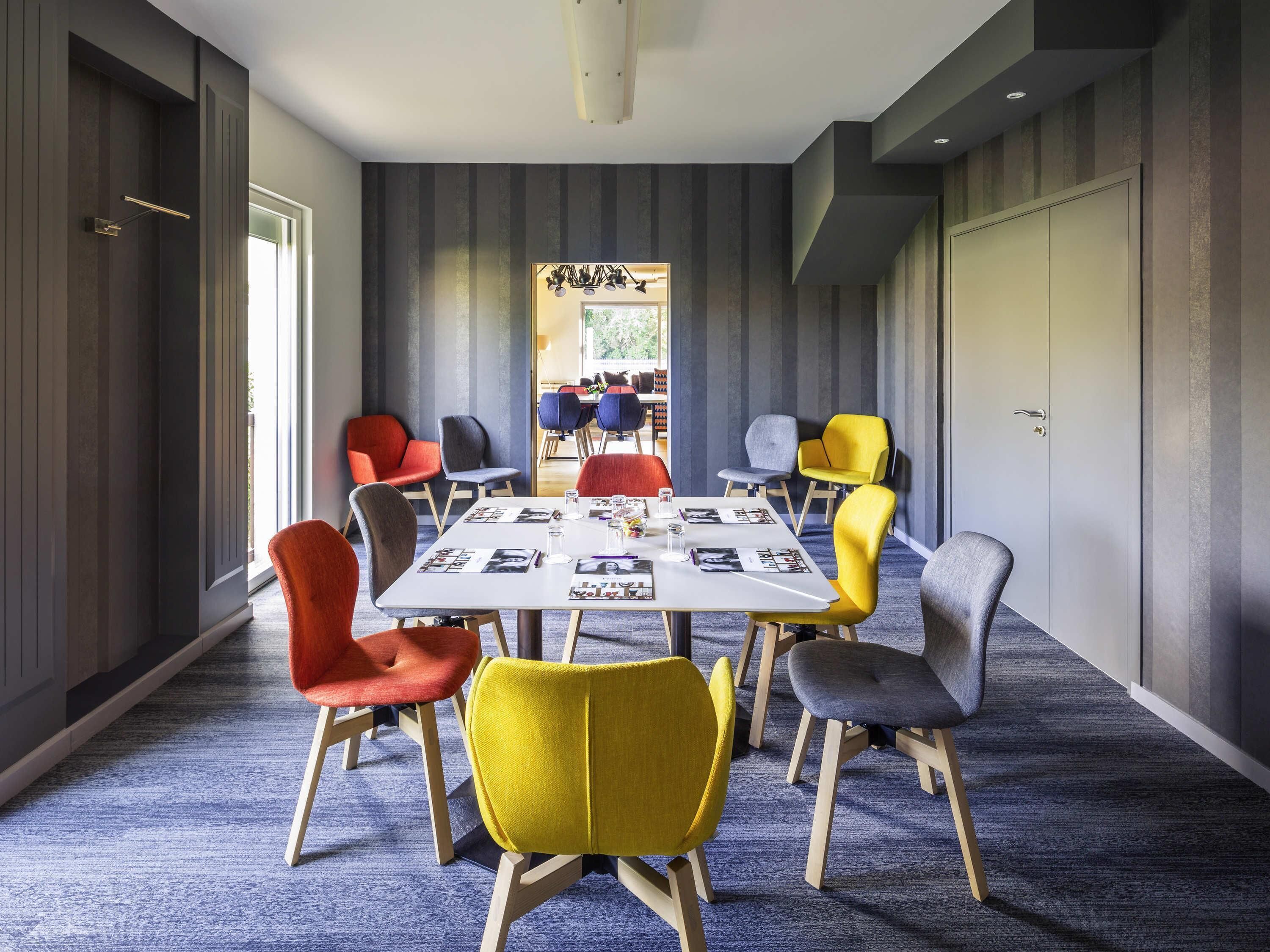 A conference room with a round table, multiple chairs, and a view of the outdoors.
