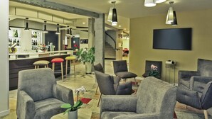 A modern living room with grey sofas, a coffee table with a plant, and a TV mounted on the wall. - Hôtel Mercure Castres L'Occitan (Castres)