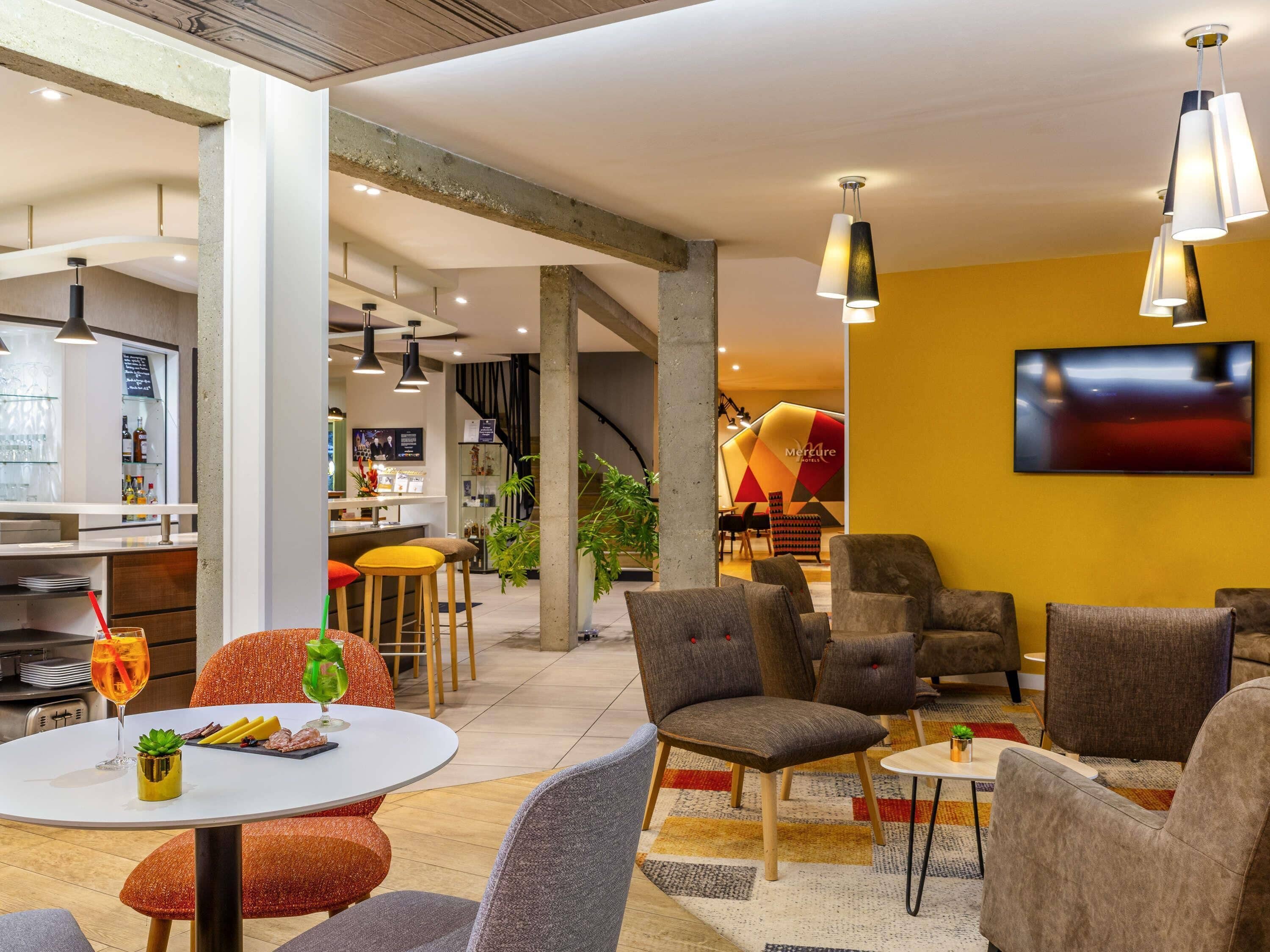 Een hotel lobby met een bar, zitplaatsen en een televisiescherm.