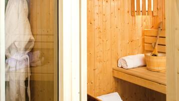Una sauna de madera con un banco, un cubo de madera y una toalla sobre el banco.