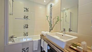 Un baño moderno con bañera, lavamanos grande y espejo.