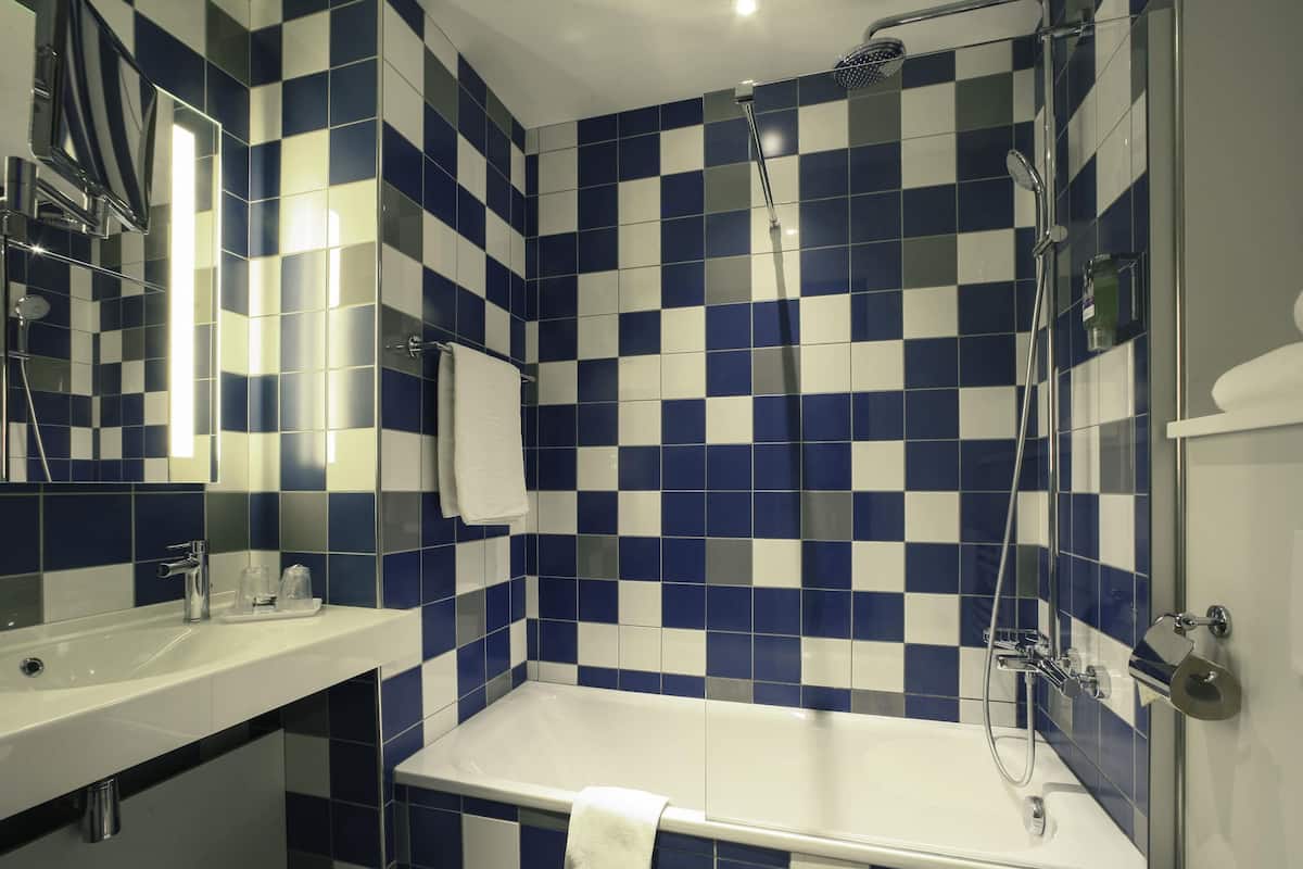 A bathroom with a checkered tile pattern, a bathtub, a shower, and a sink.