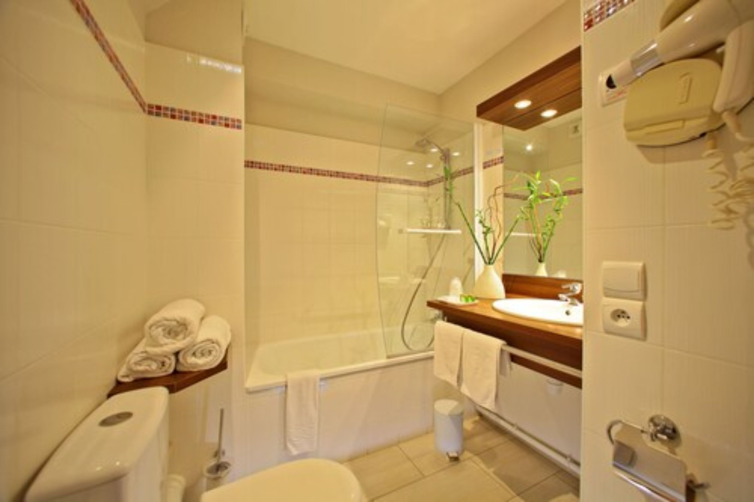 Un baño moderno con ducha envuelta en vidrio, bañera, inodoro y lavamanos con espejo.