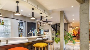 A modern bar area with stools, a counter, and a variety of bottles and glasses. - Hôtel Mercure Castres L'Occitan (Castres)