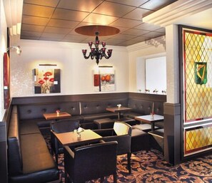 Un restaurante con zona de asientos en cabina, mesas y un candelabro.