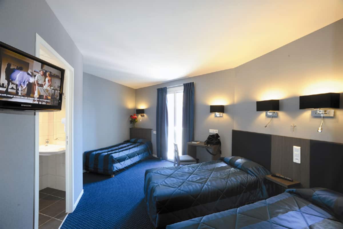 Hotelkamer met twee bedden, een bureau, een stoel, een televisie en een badkamer.