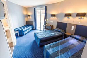 Habitación de hotel con dos camas, un escritorio y una silla. Tiene una ventana con cortinas, un televisor montado en la pared y dos apliques.