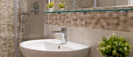 Un baño con cabina de ducha de vidrio, un lavabo blanco y un espejo encima.