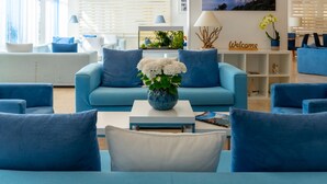 Una sala de estar moderna con un sofá azul, una mesa de centro blanca y un jarrón decorativo con flores blancas.
