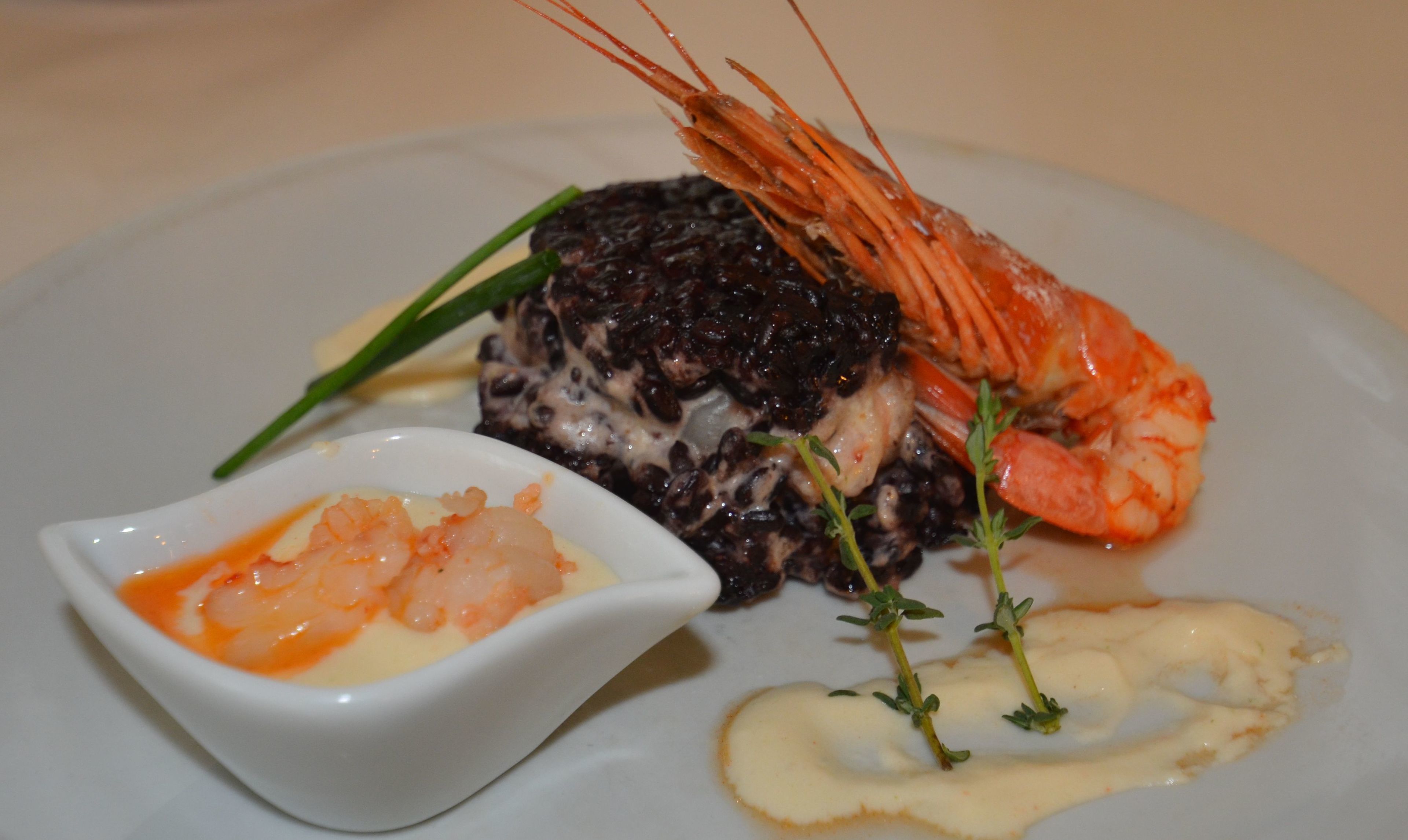 A plate with a lobster tail, a dark mushroom-based dish, and a small bowl of sauce.