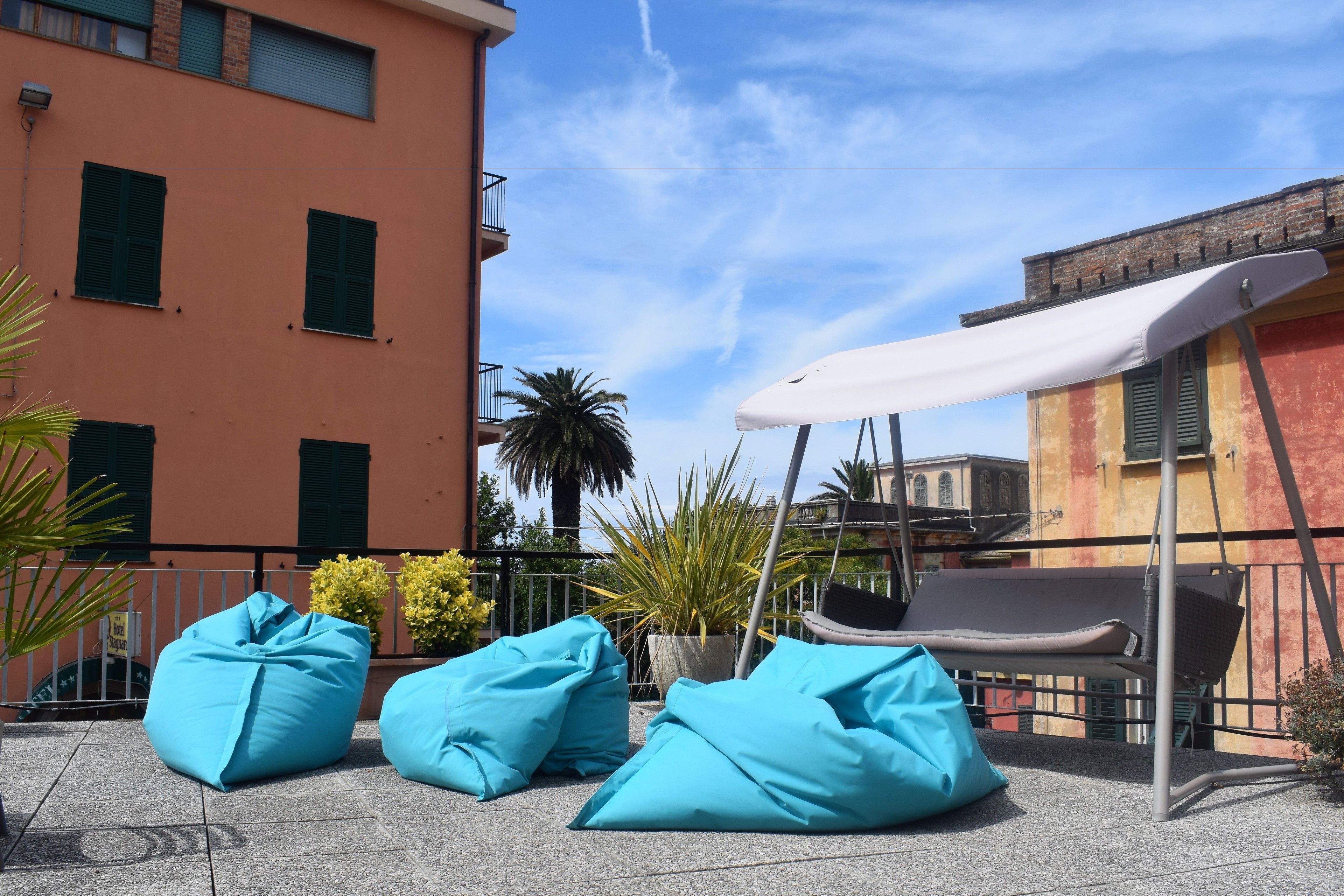 A terrace with blue bean bags, a white canopy, and a swing chair.