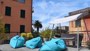 A terrace with blue bean bags, a white canopy, and a swing chair.