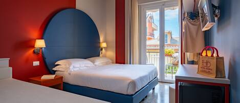 Una habitación de hotel con cama, mesitas de noche, lámpara, televisor y vistas al exterior.