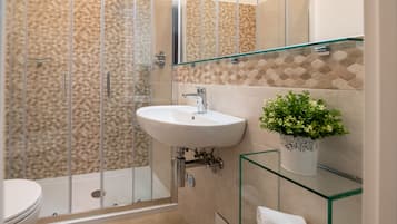 Ein modernes Badezimmer mit einer Duschkabine aus Glas, einem weißen Waschbecken und einem Glastischchen als Waschtisch.