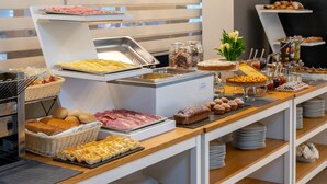 Un bufé con diferentes opciones de comida, incluyendo carnes, quesos y productos de pastelería.