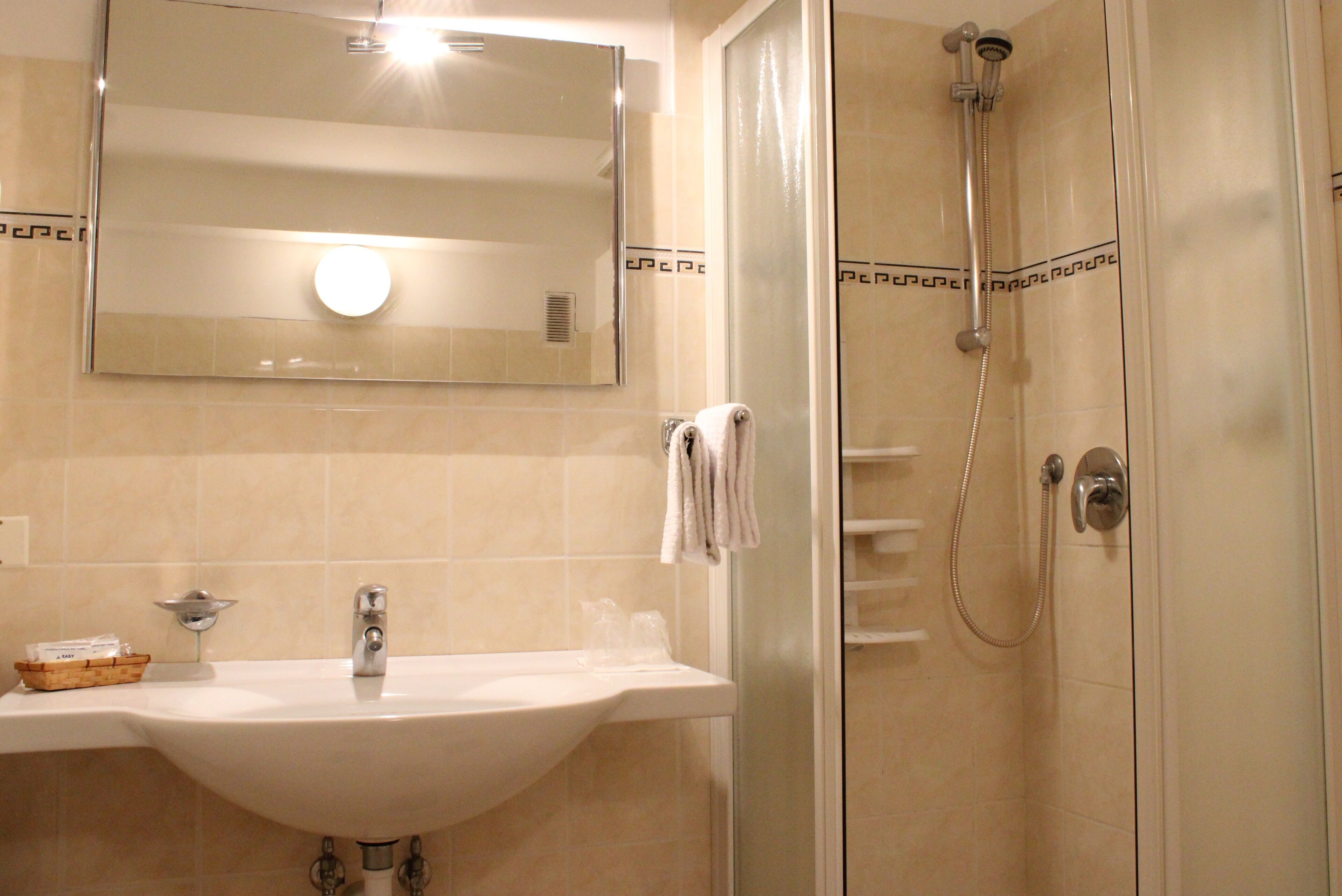 A bathroom with a sink, mirror, and shower.