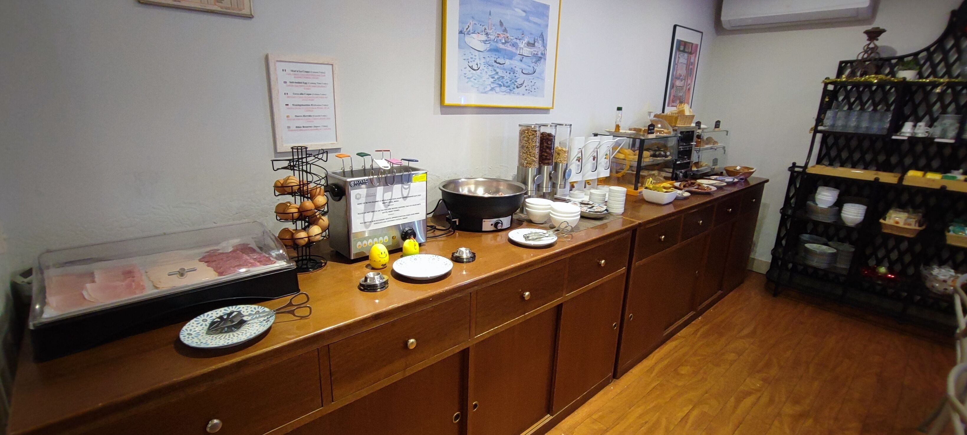 Ein Frühstücksbuffet mit verschiedenen Speisen und Beilagen, einer Kaffeemaschine und einem Weinregal.