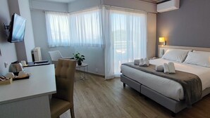 A hotel room with a bed, bedside tables, a desk, a chair, and a TV. - Hôtel Alexandra (Roquebrune-Cap-Martin)