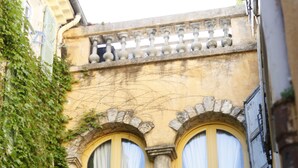 A building facade with arched windows, a balcony with a wrought iron railing, and a sign that reads "Atelier". - Hotel Les Armoiries (Valbonne)