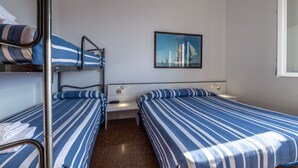 Una habitación de hotel con literas, una mesita de noche pequeña y un cuadro enmarcado en la pared.