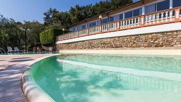 Een buitenzwembad, parasols bij het zwembad en ligstoelen