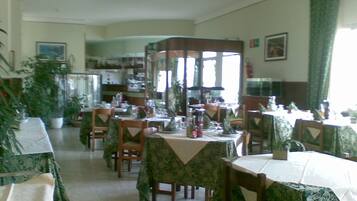 A dining area with tables set for a meal, chairs, and a large window providing natural light.