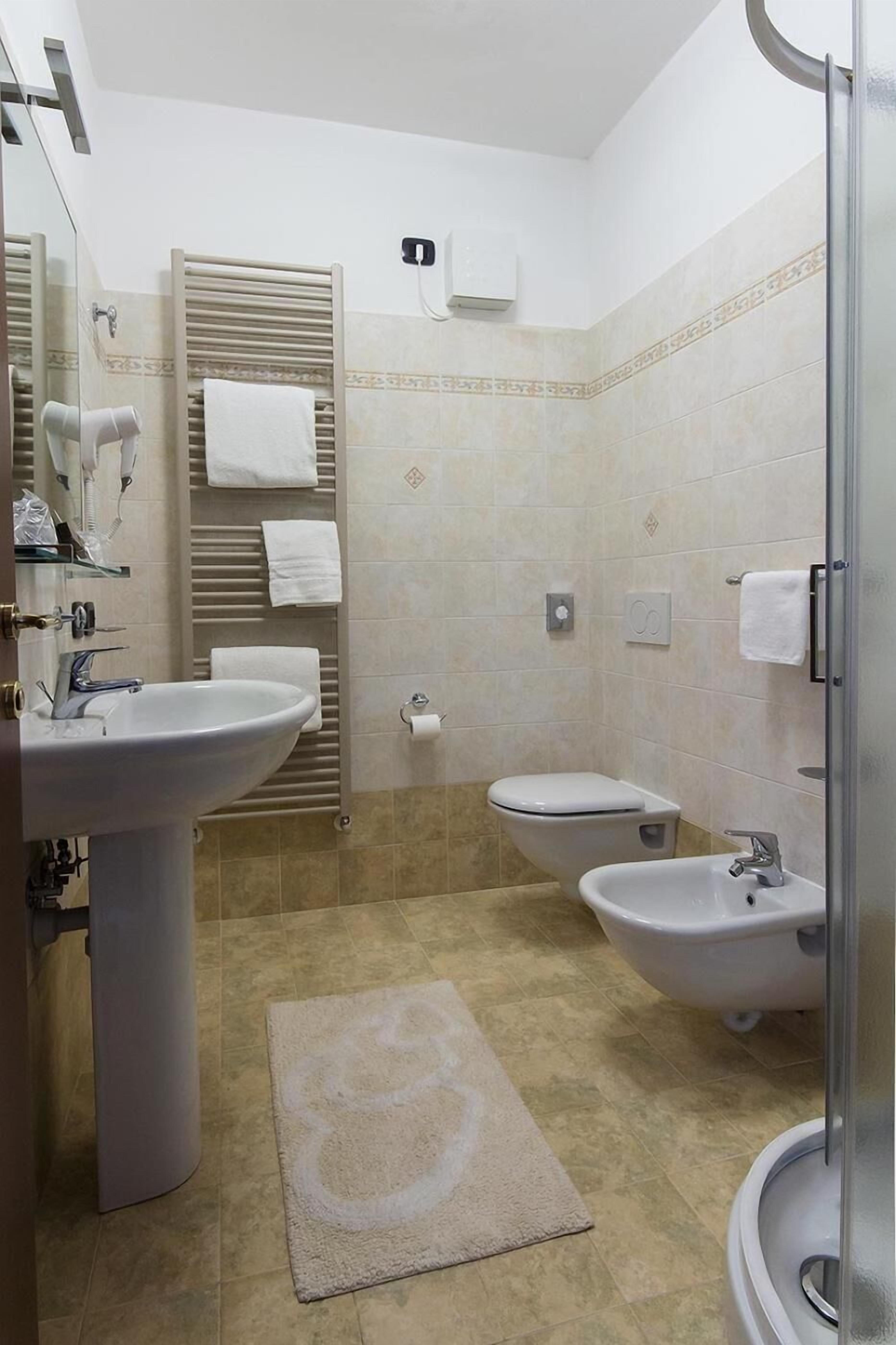 Ein Badezimmer mit Waschbecken, Bidet, Toilette, Handtuchhalter und einer Duschkabine aus Glas.