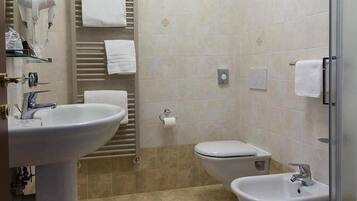 Ein Badezimmer mit Waschbecken, Bidet, Toilette, Handtuchhalter und einer Duschkabine aus Glas.
