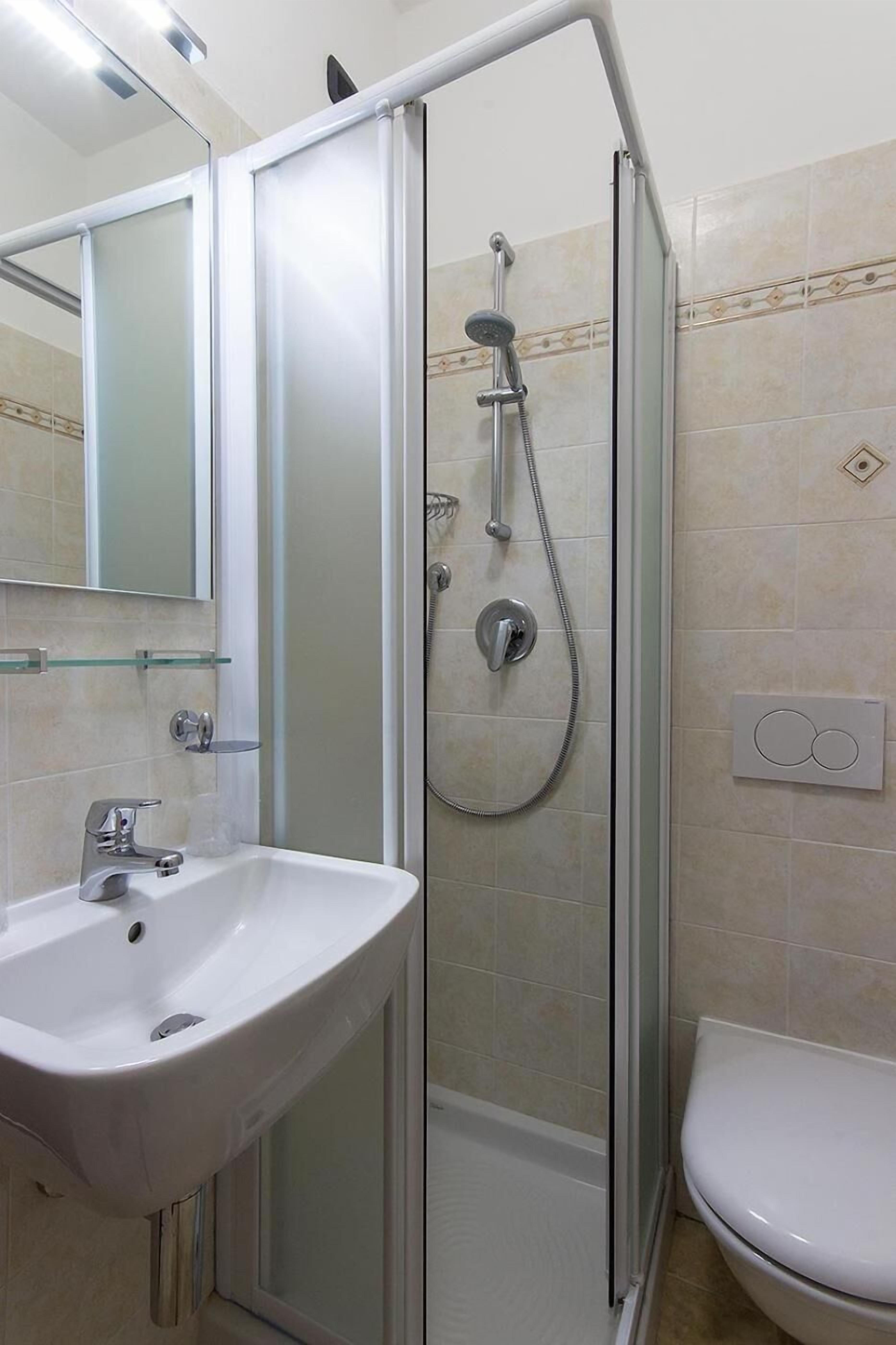 Ein Badezimmer mit einer gläsernen Duschkabine, einem weißen Waschbecken und einer Toilette.