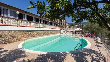 Een buitenzwembad, parasols bij het zwembad en ligstoelen