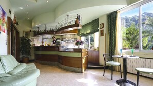 Een ruime woonkamer met een gebogen houten bar, een groene bank en een eettafel met stoelen.