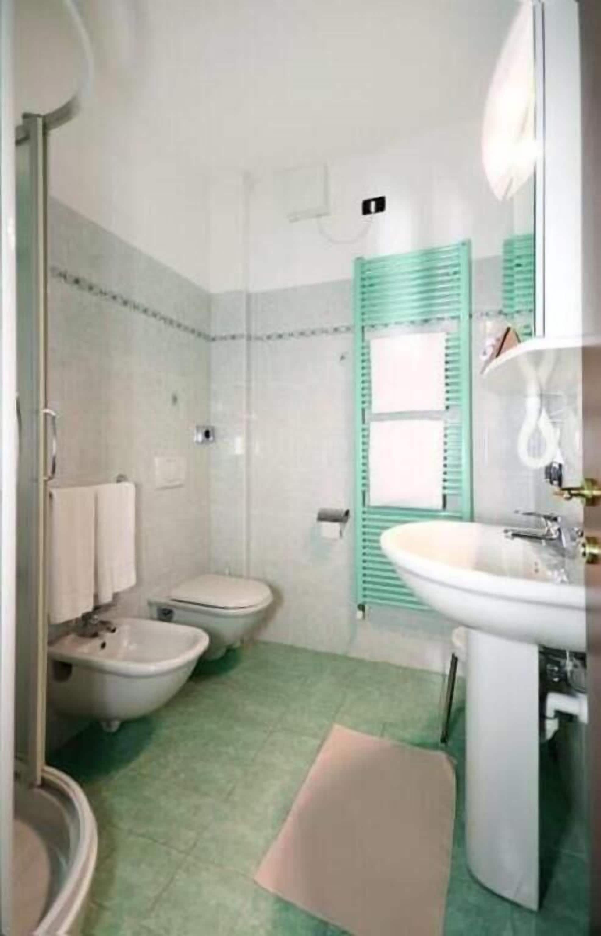 Un baño con inodoro, bidé y lavamanos.