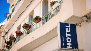 Un letrero de hotel con un balcón decorado con plantas en macetas.