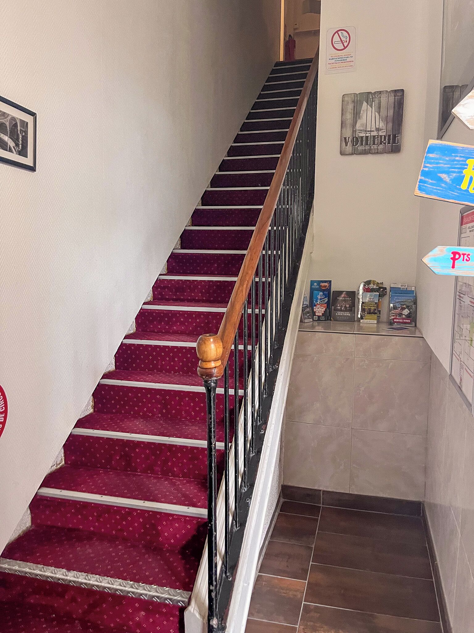 Un escalier recouvert d’une moquette rouge et doté d’une rampe en bois, menant à l’étage supérieur.