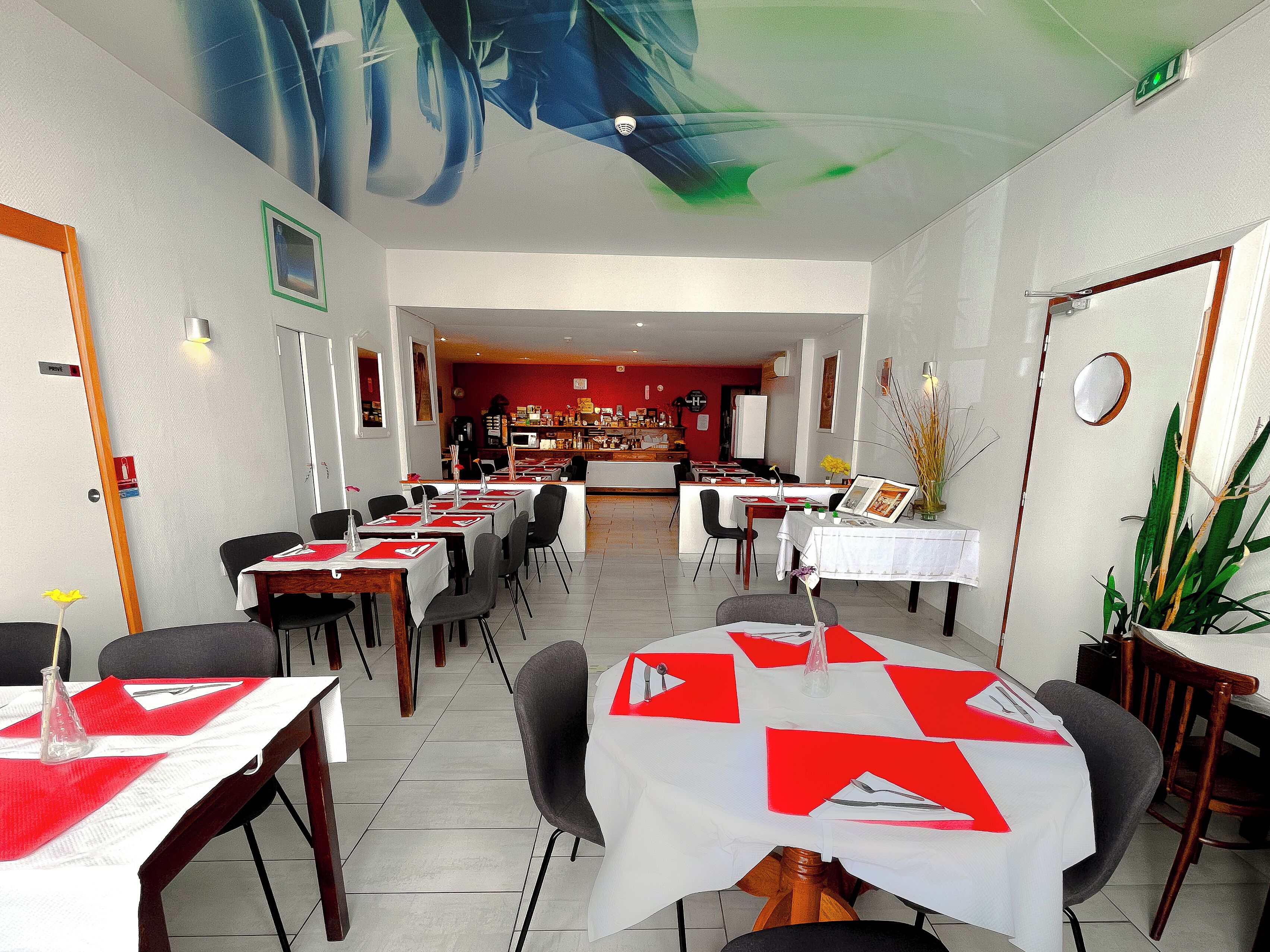 En restaurant med dækkede borde, et barområde i baggrunden og et loftsmaleri.