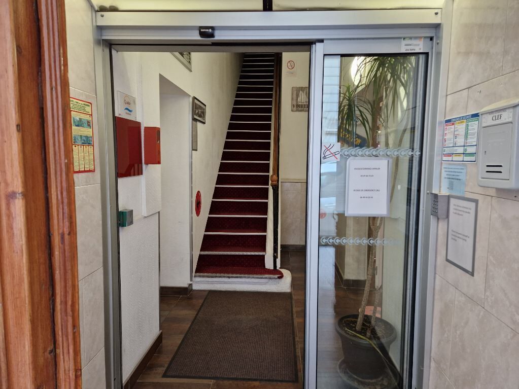 Ein Hotel Eingang mit Glastür, Treppe und einer roten Teppich, der zu den Stufen führt.