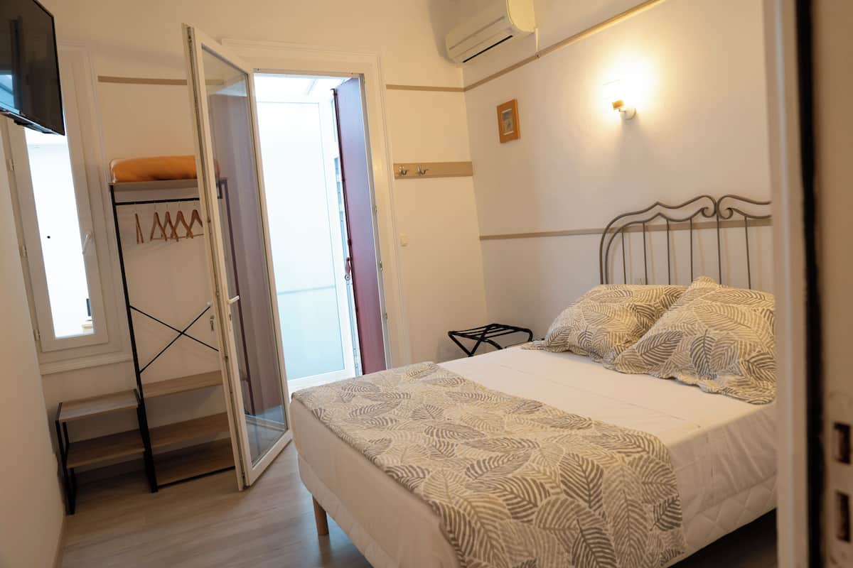 Un dormitorio con cama, armario, puerta que da a un espacio exterior y aire acondicionado instalado en la pared.