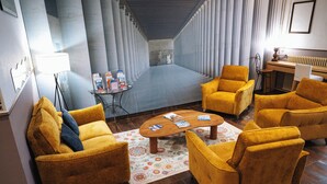 A modern interior with a sofa set, a coffee table, and a patterned rug. - Hôtel Le National (Sète)