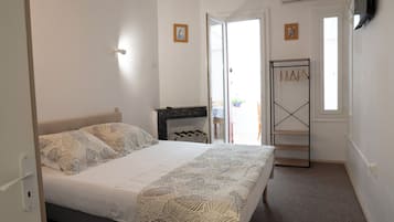 A bedroom with a bed, a wardrobe, a door leading to a balcony, and a wall-mounted TV.