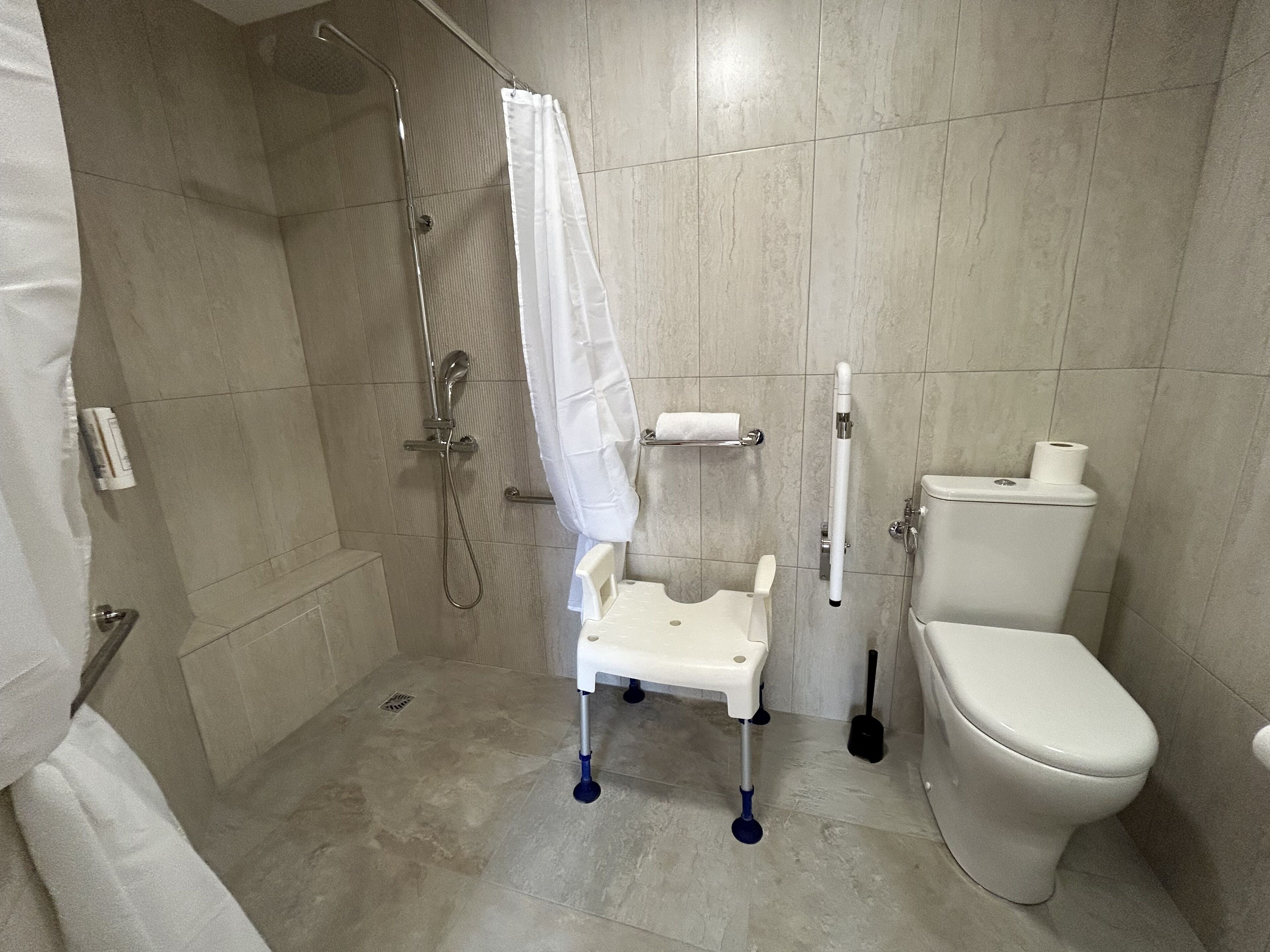 Un baño con ducha, inodoro y barandilla.