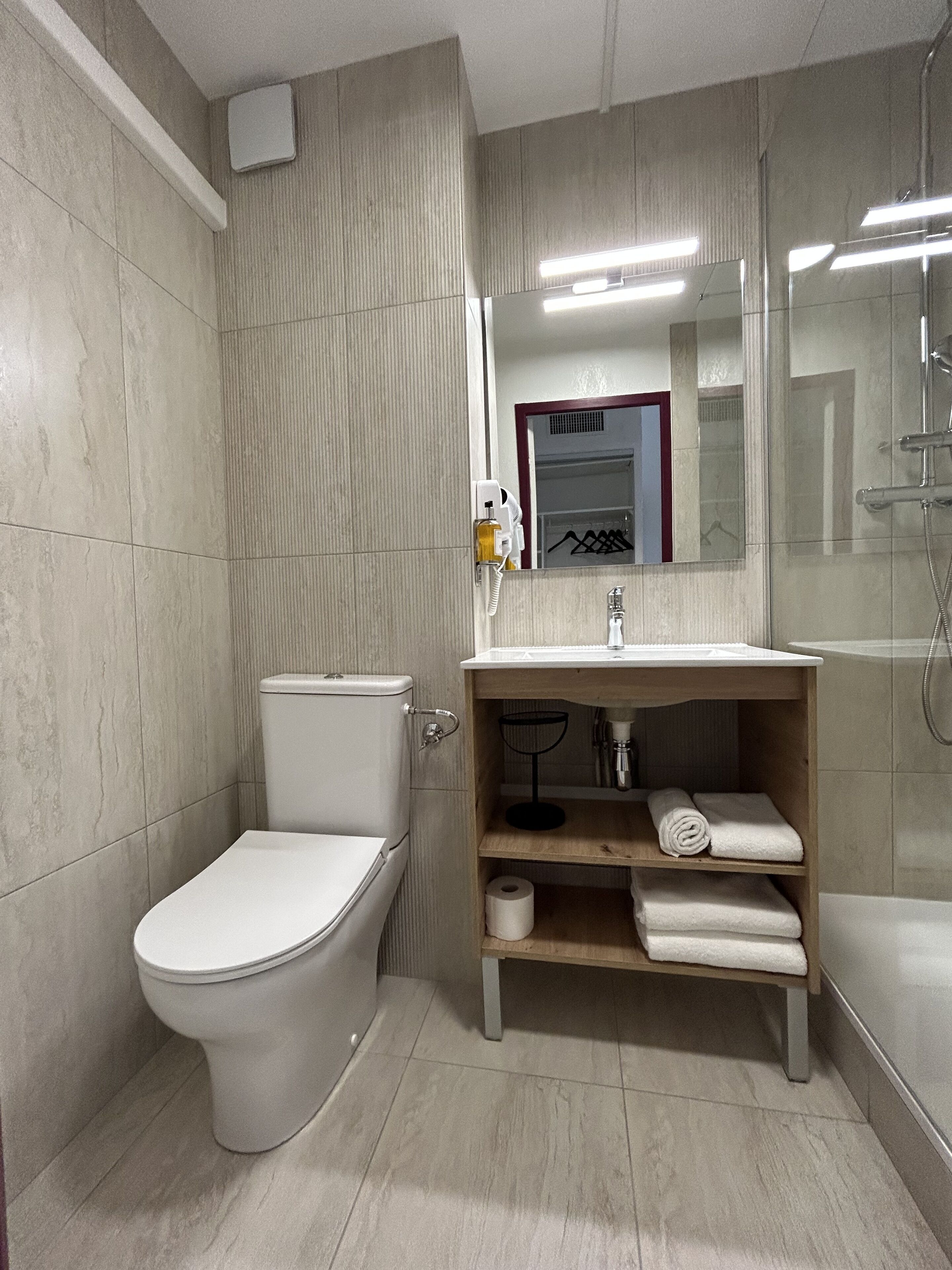 Une salle de bain moderne comprenant des toilettes, un lavabo avec un miroir et un espace douche.
